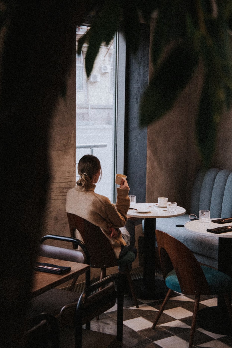 Gast mit einer Tasse Kaffee am Fenster eines kleinen Cafés